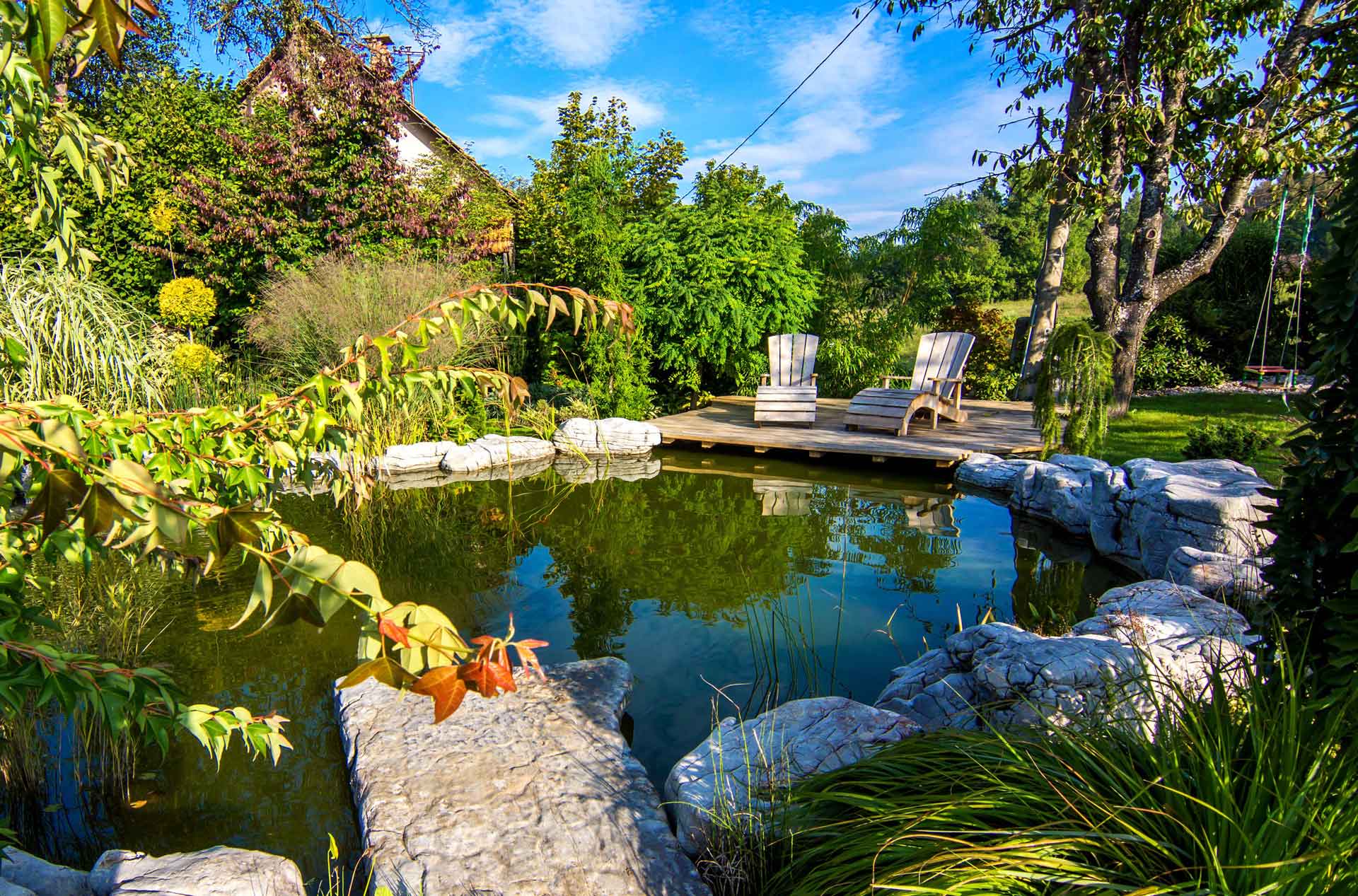 Wunderschöne Teichanlage in einem blühenden Garten mit Holzterrasse