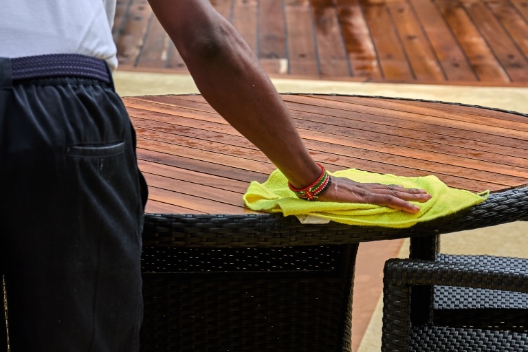 Worker with Kenyan bracelet cleaning outdoor furniture
