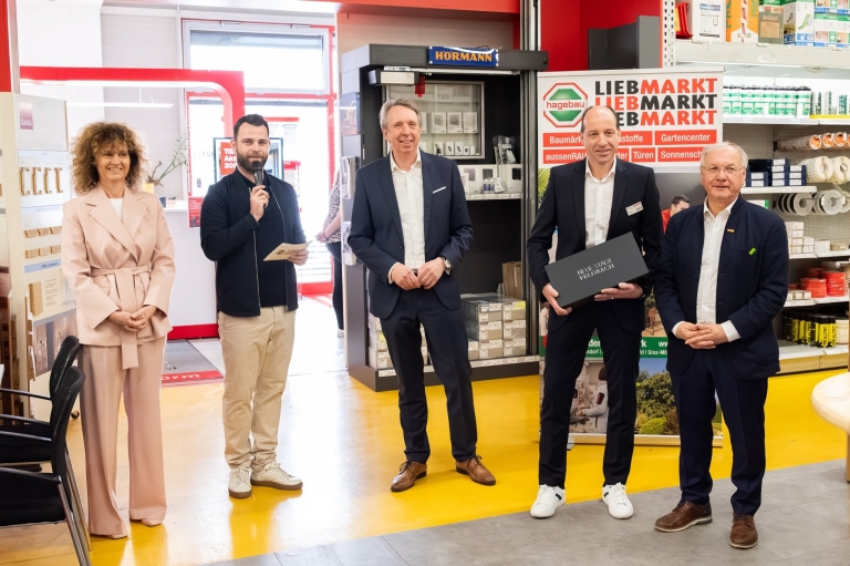 Gruppenfoto_WEB Veranstaltung im Baumarkt mit mehreren Anwesenden auf der Bühne
